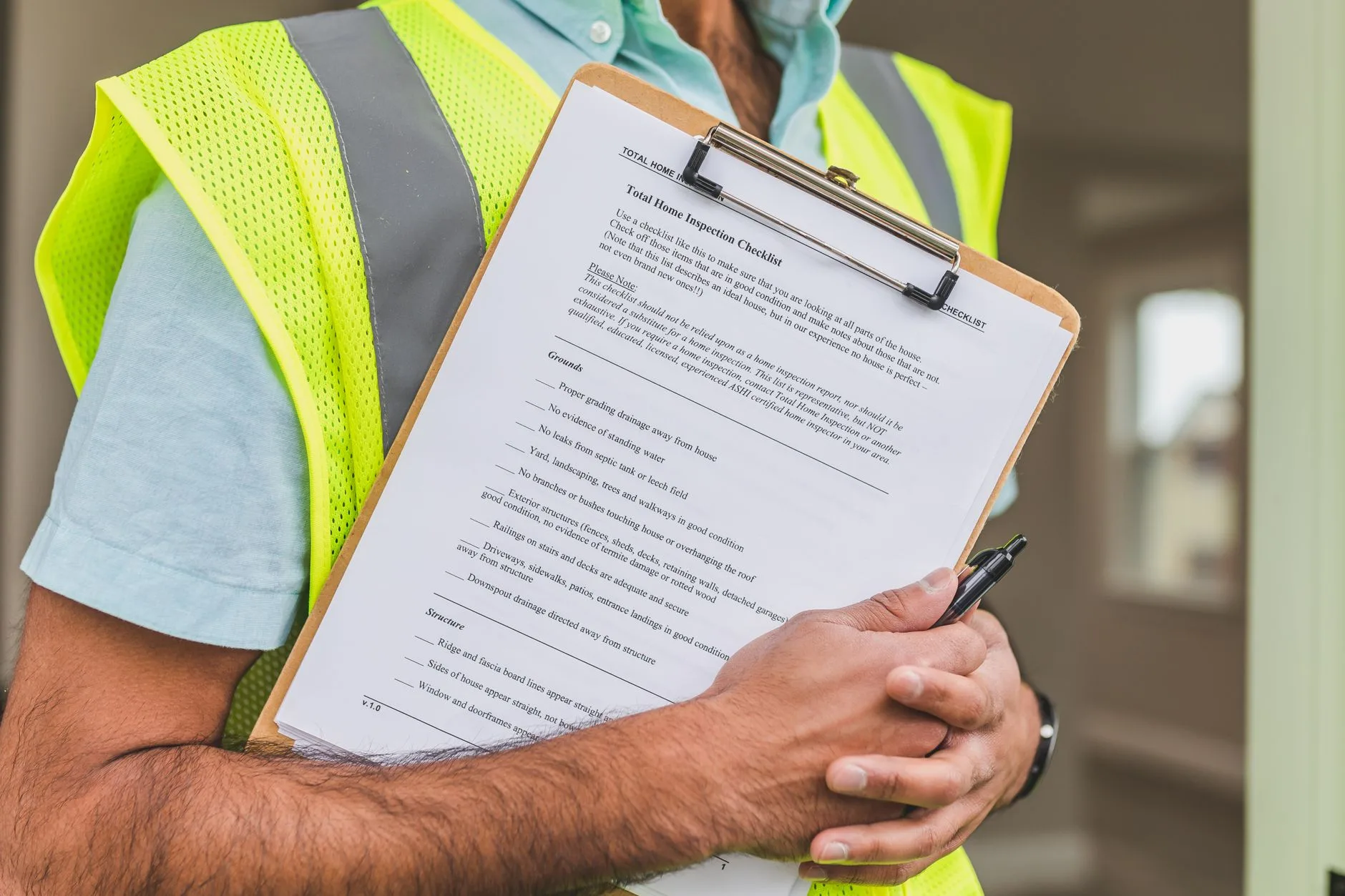 Inspector in a safety vest holding a home inspection checklist on a clipboard
