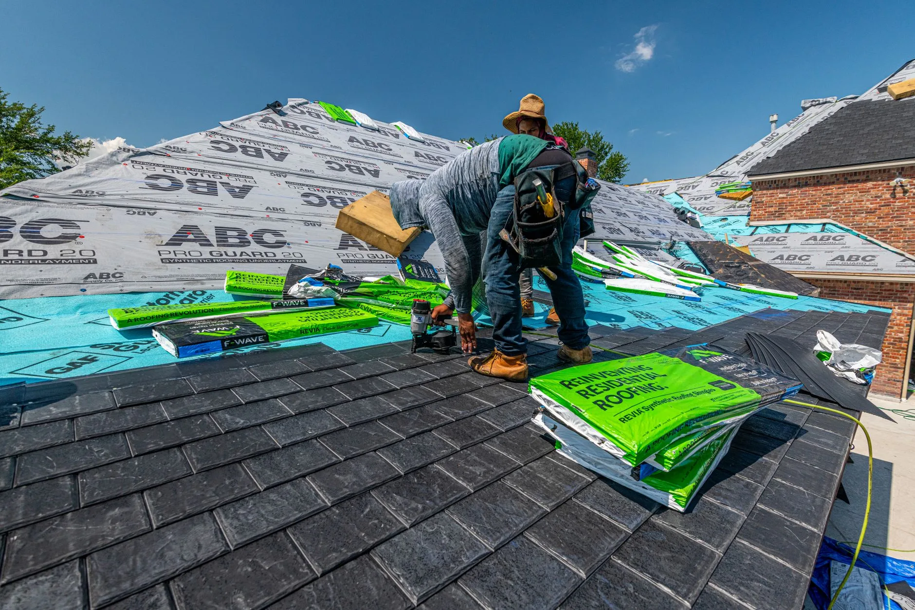 Roofer laying new shingles over fresh underlayment on a house roof