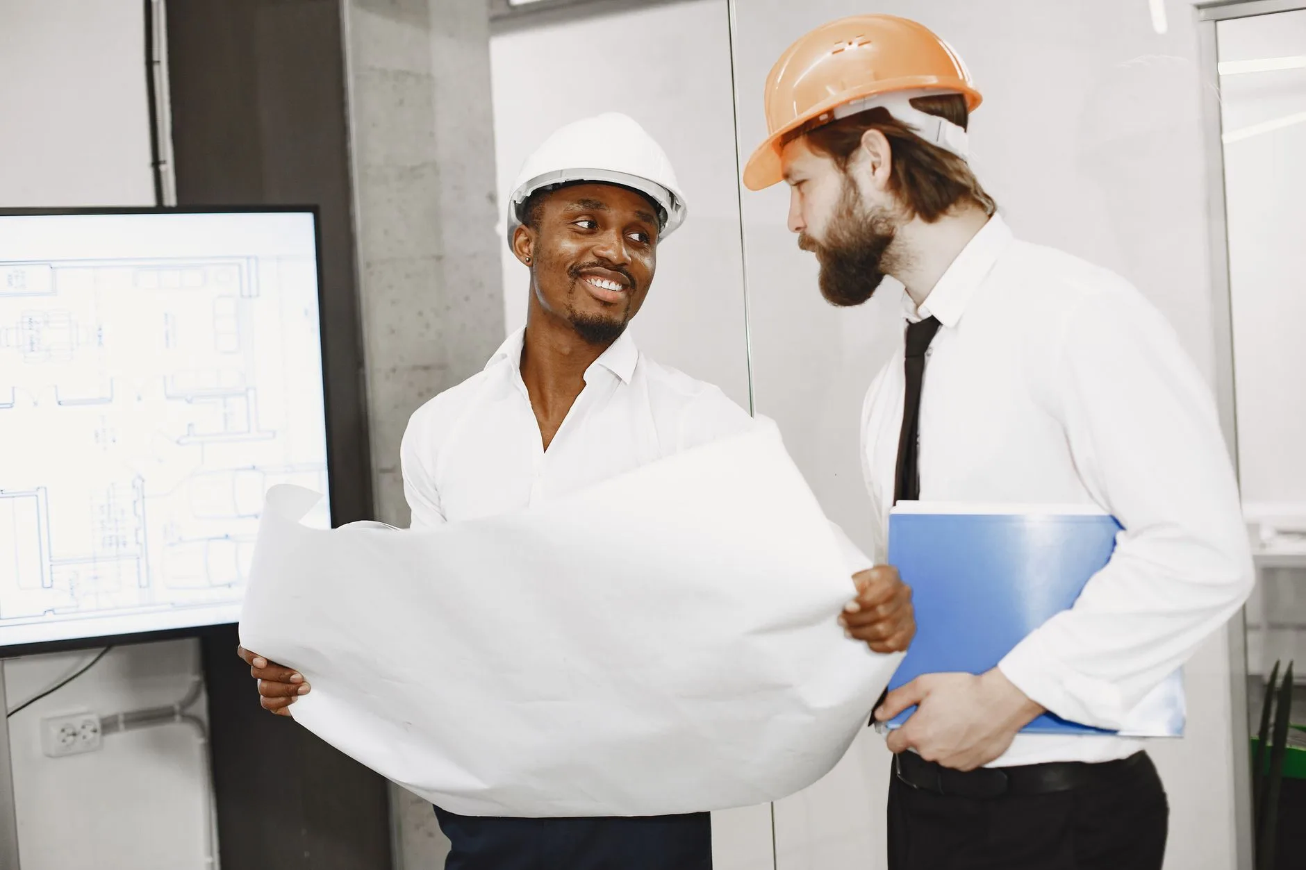 Two professionals reviewing building plans and permit paperwork together